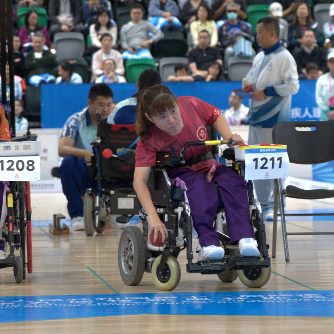 During a boccia competition, athlete Karen Kwok leans forward in her wheelchair, using upper body strength for an accurate, focused throw.